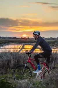 Cycliste devant un marais salant au coucher de soleil
